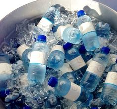 a bucket filled with lots of blue and white water next to another container full of bottled water