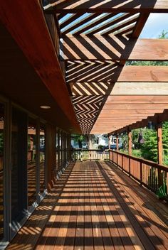 a long wooden walkway with lots of windows and wood slats on the side of it