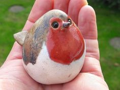 a hand holding a small bird figurine in it's palm