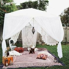 an image of a tent set up in the yard with pillows and blankets on it