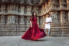 a man and woman standing in front of an intricately carved wall