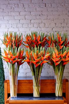 three vases filled with orange flowers on top of a wooden bench