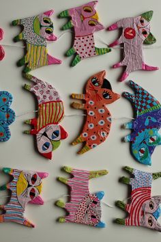 colorful paper cut out animals hanging from clothes pins on a white surface with strings attached to them