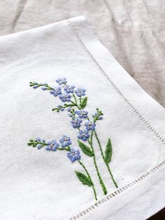 a close up of a napkin with blue flowers embroidered on the front and back of it