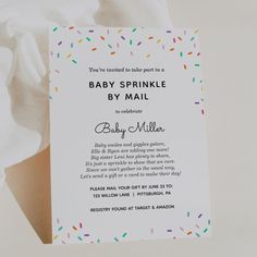 a baby sprinkle by mail card is laying on a white sheet with colorful sprinkles