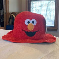 a red sesame character hat sitting on top of a bed