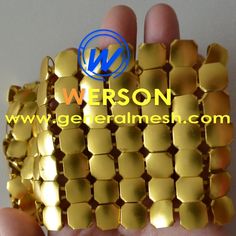 a hand holding a gold colored metal mesh