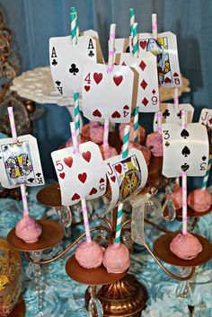 a table topped with lots of desserts and playing cards on top of it's sticks