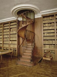 a spiral staircase in the middle of a library with bookshelves on either side