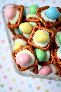 some pretzels and candy are in a glass dish on a table with confetti