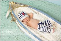 a baby laying in a boat on top of a bed