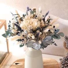 a white vase filled with lots of flowers on top of a table