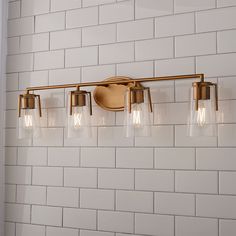 a bathroom light with four bulbs on the wall and white brick walls behind it,