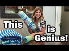 a woman is sitting on the floor with some folded towels in front of her, and there are two pictures behind her