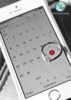 a cell phone with a ring on it's screen sitting on a table next to a calendar