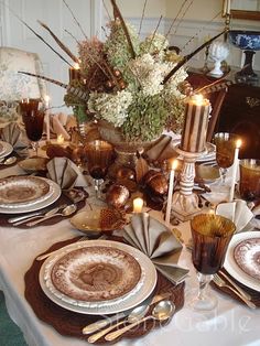 a table set with plates, silverware and candles