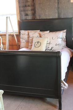 a bed with pillows on top of it in a bedroom next to a wall and window