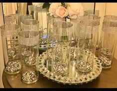 a table topped with lots of glass vases and glasses on top of a wooden table