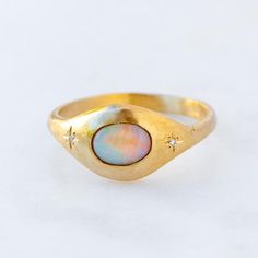 Our Orbit signet style ring has been set with a black opal from Lightning Ridge with two star set diamonds either side. Opals are the birthstone of October. Opal measures 7 x 5 mm. F/VS Diamonds total weight 0.01ct. Band width at back 2.2 mm Please note, we will match the opal as close to the image as possible. Each opal is unique and may vary in appearance and colour from what is depicted on the site. Diamond Star Ring, Opal Signet Ring, Sarah Gardner Jewellery, Non Diamond Rings, Lost Wax Casting Rings, Eclipse Ring, Sarah Gardner, Opal Gold Ring, Asymmetrical Ring