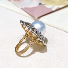 This royal style ring using Italy Buccellati process. Product Information OriginSouth Sea Pearl Jewelry Processed in Japan MaterialSouth Sea Pearl, 18k Gold and Natural Diamond DimensionsTop Approx. 3.0 x 2.7 cm Pearl Shaped: Round Size: 14 mm Quality: AAAA Nacre: Very Thick Color: White Luster: Very High Accessories Metal: 10.5g of 18k Gold and White Gold Other: 0.85ct of Natural Diamond Luxury Pearl Ring With Diamond Pave Setting, Luxury White Gold Dome Ring With Gemstone, Luxury White Diamond Dome Ring, Luxury Dome Ring With 17 Jewels, Luxury Dome Ring With 17 Jewels For Anniversary, Luxury White Dome Ring With Brilliant Cut, Luxury Dome Ring With Pave Setting As Gift, Luxury Dome Ring With Pave Setting For Gift, Luxury White Rings