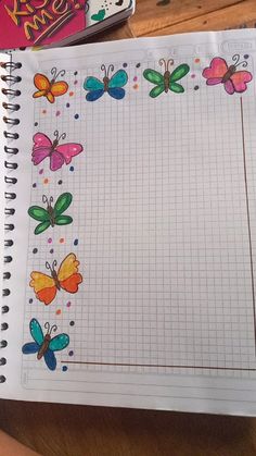 an open notebook with colorful butterflies on it next to a pencil and eraser box