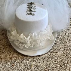 "Wedding white, felt top hat with accents of white tulle, silver leaf trims accented with silver pearls.  Hat encircled with triple layered lace with white pearls.  Front Veil covers face and neck and can fold back to enhance back veil.  Back white tulle veil is approx. 18\" long.  Silver leaf trim comes up the back of top hat and continues on the top of hat.    Fits most adult heads.  Includes white adhesive padding strips to reduce size of opening. All my designs are one-of-a-kind.  Made in a peaceful setting in Lakeside, OR USA Props not included." Fitted Tulle Hats For Weddings, White Costume Hat With Round Crown For Parties, White High Crown Top Hat For Church, White High Crown Costume Hat For Church, White High Crown Hat For Church, Whimsical White Costume Hats And Headpieces For Party, Wedding Top Hat For Halloween, White Tall Crown Headpiece For Parties, White Mini Hats For Halloween Party