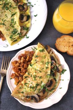 an omelet with mushrooms and other food on plates next to a glass of orange juice