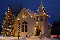 a white church with christmas lights and wreaths on it