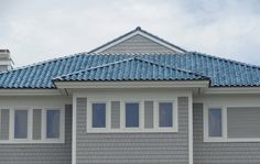 a gray house with blue roof tiles and windows