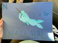 a child holding up a sign with an image of a narwhale on it