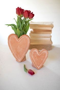 two heart shaped vases sitting next to each other with tulips in them