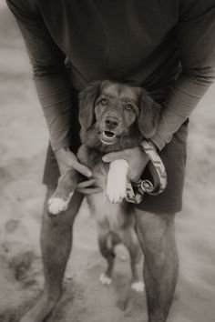 a man holding a dog in his arms on the beach, black and white photo