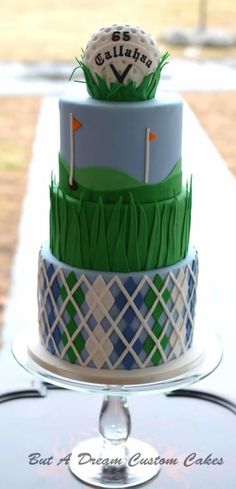 a cake that is on top of a glass stand with a golf ball and flag