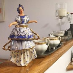 there is a figurine that is on the shelf next to cups and saucers