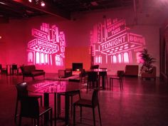 an empty room with tables and chairs lit up by red lights on the wall behind them