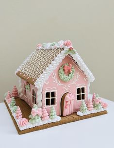 a pink and white gingerbread house on a table