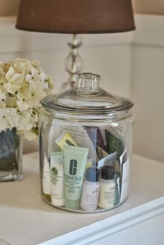 a glass jar with some skin care products in it and a lamp next to it