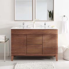 a bathroom vanity with two mirrors above it and a rug on the floor next to it