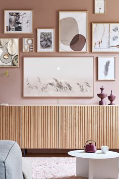 a living room with pink walls and pictures on the wall, including a coffee table