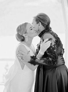 two women kissing each other in front of a window