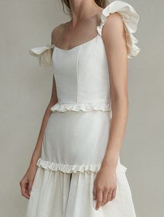 a woman wearing a white dress with ruffles