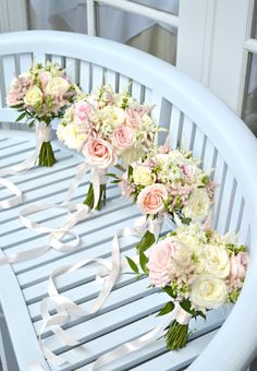 three bouquets of flowers sit on a white bench with ribbons tied around the edges