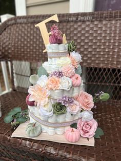 a three tiered wedding cake decorated with flowers and leaves on a wicker table