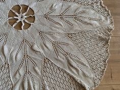 a crocheted doily on a wooden floor with a circular object in the middle