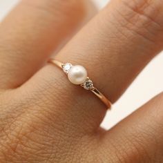 a woman's hand with a pearl and diamond ring on top of her finger