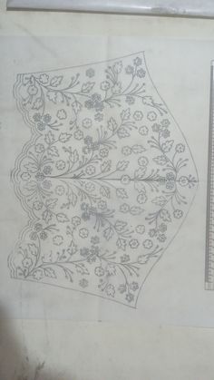 an old piece of cloth with flowers and leaves on it, next to a ruler