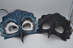 two masks are sitting on a table next to each other, one is black and the other is blue