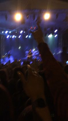 the audience at a concert is holding their hands up in the air to catch something