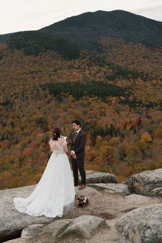 a bride and groom standing on top of a mountain