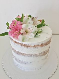 a white cake with pink and white flowers on top is sitting on a platter